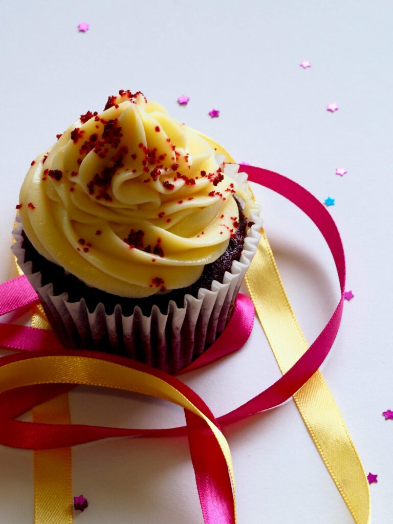 Gluten Free Life: Chocolate cupcake with yellow frosting, red sprinkles, and ribbons on star confetti.