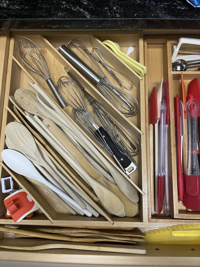 Organize small kitchen spaces with trays holding wooden spoons, metal whisks, spatulas, and other essential utensils.