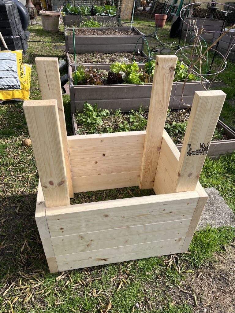 An inverted wooden planter box in a garden hints at 6 Best Ways to Plant Potatoes for a Bountiful Harvest.
