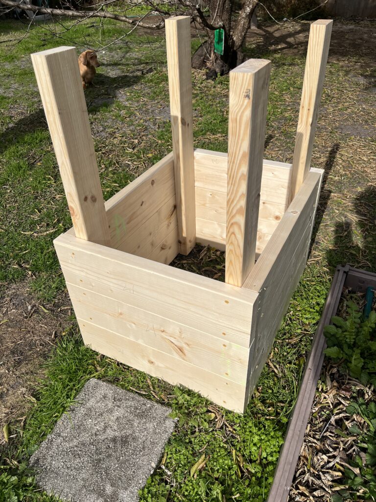 A wooden planter box, perfect for 6 Best Ways to Plant Potatoes, sits upside down on grass in a sunny backyard.