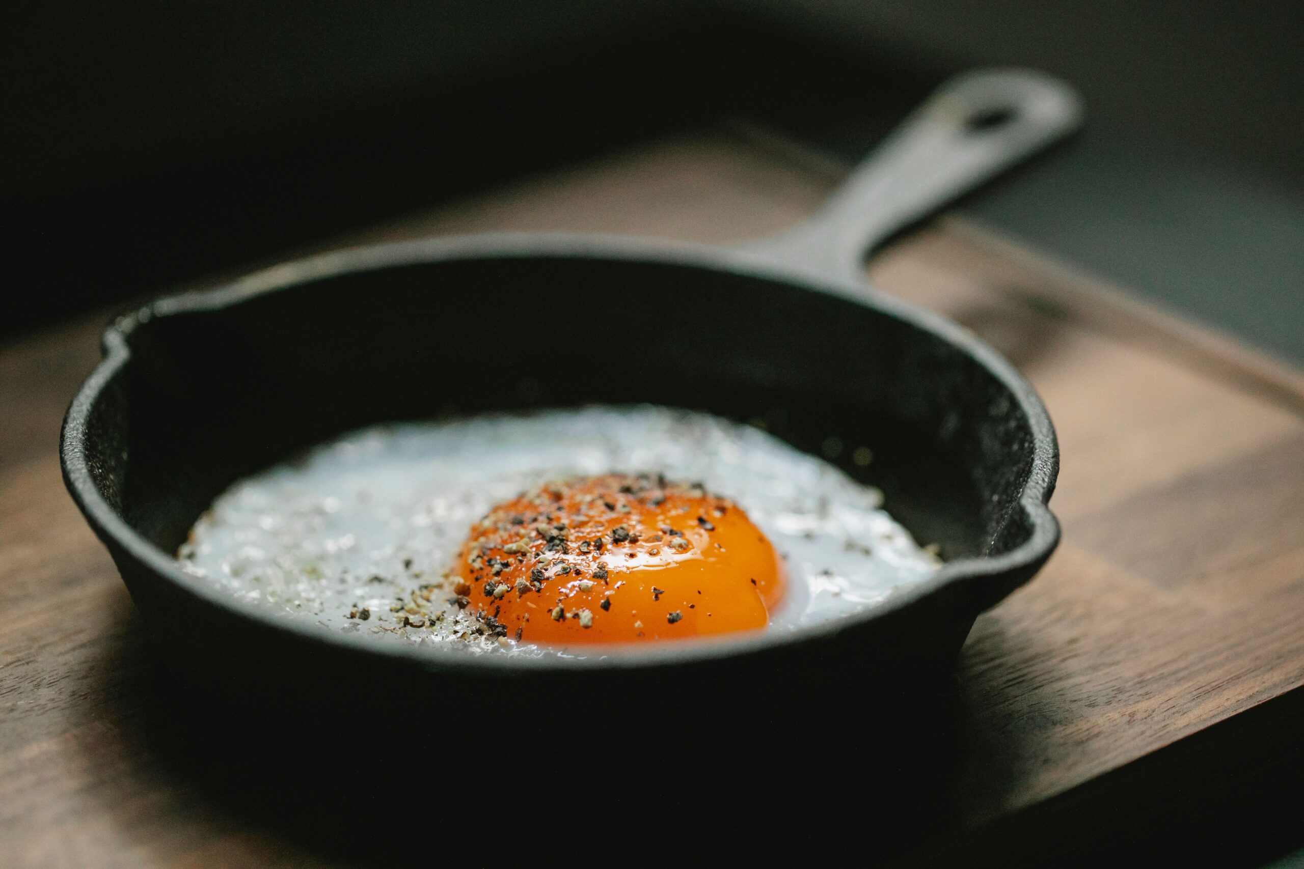 Fried egg cooked in a skillet, plated on a wooden board