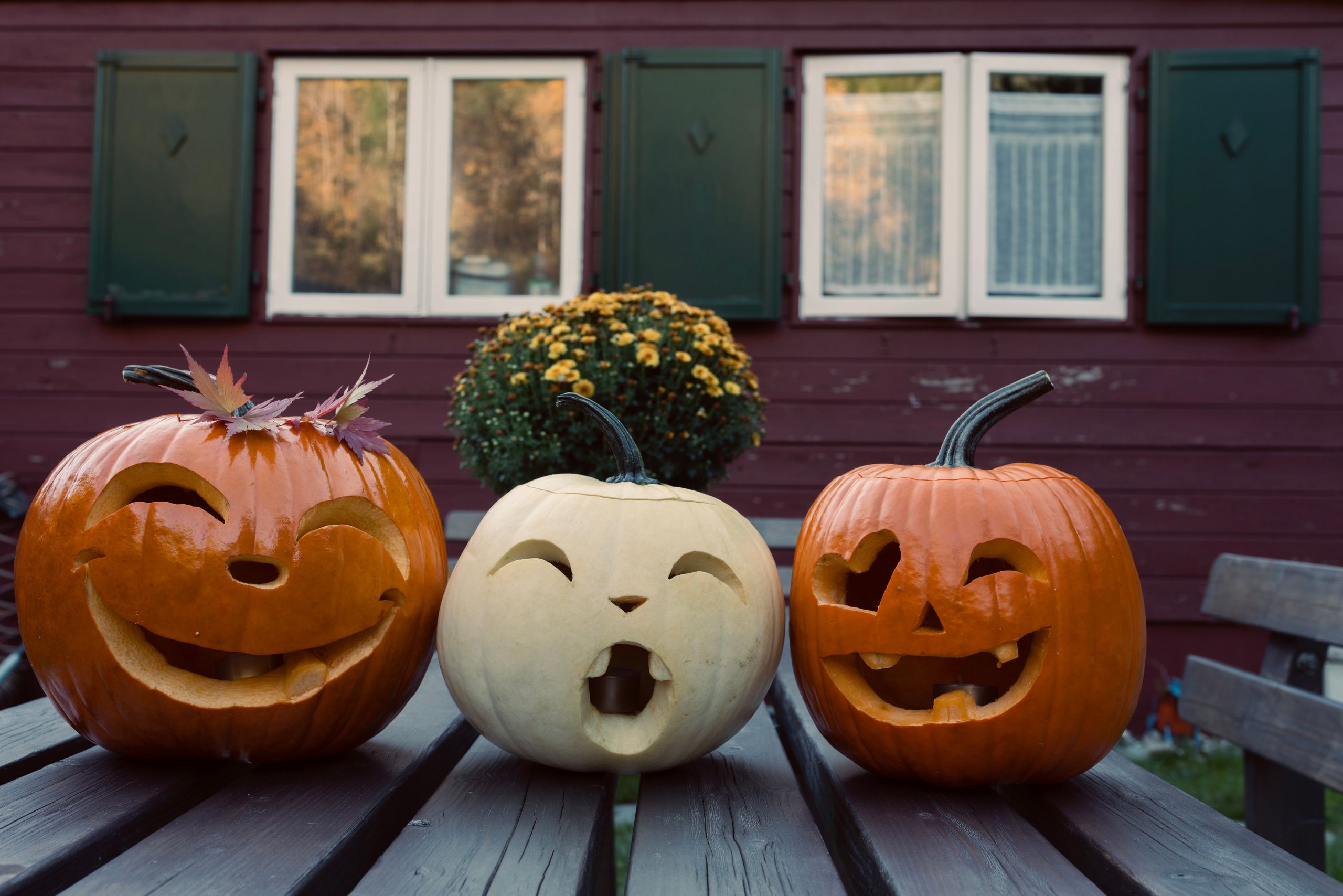 Vintage Halloween decorating ideas with three carved jack-o’-lantern pumpkins on a wooden table.