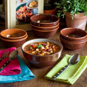 A bowl of bean and vegetable soup surrounded by empty bowls and colorful napkins.